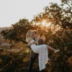 man carrying woman wearing white dress during sunrise