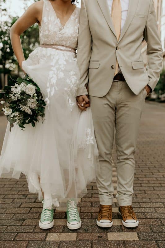 man in gray suit jacket and woman in white wedding dress holding bouquet of white flowers
